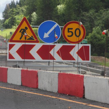 Yol çalışması, trafik oku yönü işareti ve hız limiti. Yaz günü yolun sağ şeridinde kırmızı beyaz bariyer üzerinde 50 işareti.