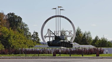 Moscow region, Dmitrov district / Russia - 08 21 2020: Soviet tank monument near road sign Dmitrov city on the Dmitrov highway on a summer day clipart
