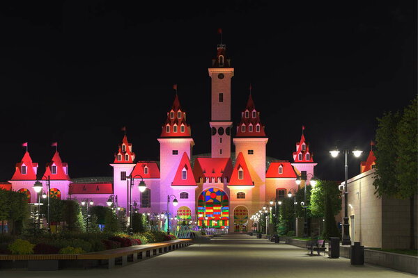 Moscow / Russia  09 02 2020: Main alley of fairytale family children's Park Island of Dreams on summer night in Kozhukhovo district, a magic castle with towers, favorite vacation spot for Muscovites