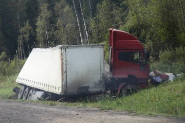 Yol kenarındaki hendekte yarı römorklu hasarlı bir kamyonet. Trafik kazası, kayma, ağaçların arkasındaki yaz yolu kazası.