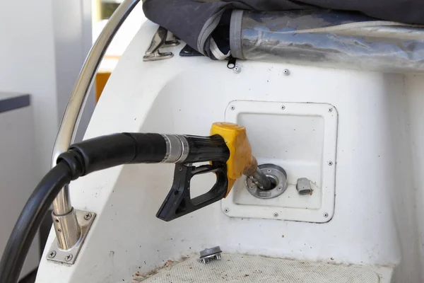 Close up yellow fuel gun in motor boat fuel filler socket on gas station, watercraft refueling