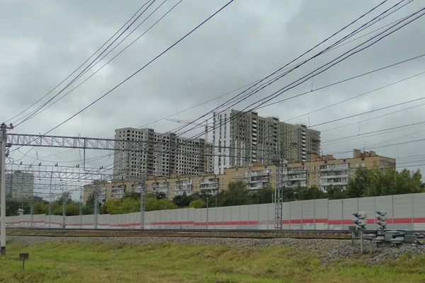 Empty electric railway near residential houses on wires background at cloudy summer day