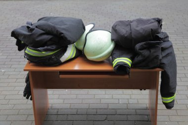 Kurtarma itfaiyecileri koruma ekipmanları. Dışarıdaki masaya yakın durun. İtfaiye kaskı, özel yangın geçirmez giysiler, eldivenler.