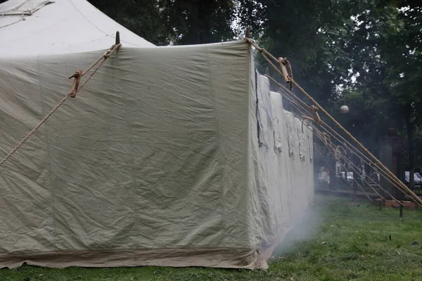 Big military tent with smoke, rescuer firefighter training site in Park on summer day