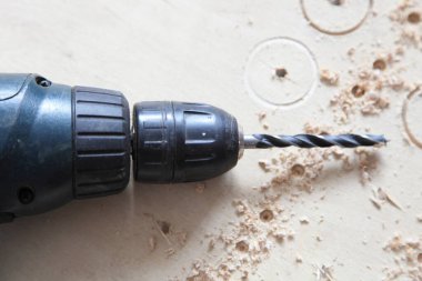 Elektrikli tornavida matkapla delme makinesi. Tahtaya yakın uç, kontrplak delme deliği.