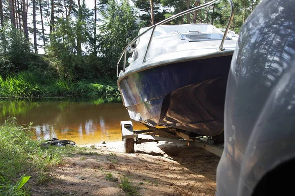 Cabin motor boat launch on forest sandy shipway, a car puts a boat on trailer in water on beautiful lake at Sunny summer day close up, boating tourism lifestyle