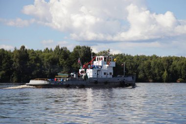 Güzel, eski bir Rus teknesi Volga Nehri 'nde yüzüyor orman ağaçları üzerinde su ve mavi bulutlu gökyüzü arka plan manzarası, kargo taşımacılığı lojistiği su taşımacılığı