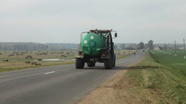 Yeşil gübreli eski traktör karavanda asfaltlanmış kırsal yolda sonbahar gününde tarla, tarım makineleri taşıma ekipmanları, dikiz görüşü