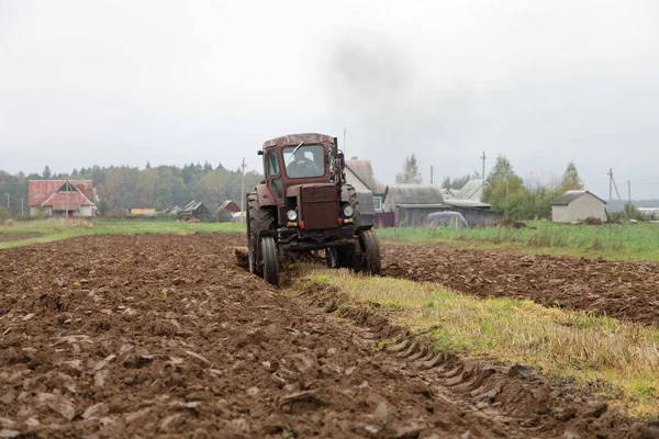 구소련의 바퀴달린 트랙터 앞쪽에는 쟁기질을 농부들이 일하는 가을에 농사를 배경에 — 스톡 사진