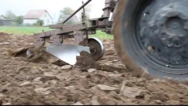 Kahverengi tarlayı süren eski üçlü metal saban. Traktör tarafı dikiz aynası, sonbahar günü toprak ekimi, kırsal tarım makineleri.