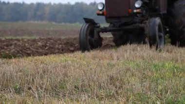 Eski Sovyet 4x4 tekerlekli kahverengi Diesel traktörü tarlayı tarla sürerek tarlayı tarlaya sürerken ön bahçeye yakın, sonbahar günü toprak ekimi, endüstriyel tarım.