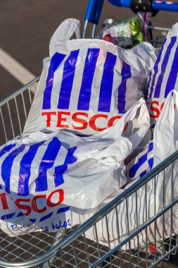 Londra, İngiltere, 19 Kasım 2011: Müşteri alıcısı, Brent Park Wembley stok fotoğrafındaki Tesco Extra süpermarket perakende satış mağazasında plastik çanta dolu bir alışveriş arabasını itiyor.