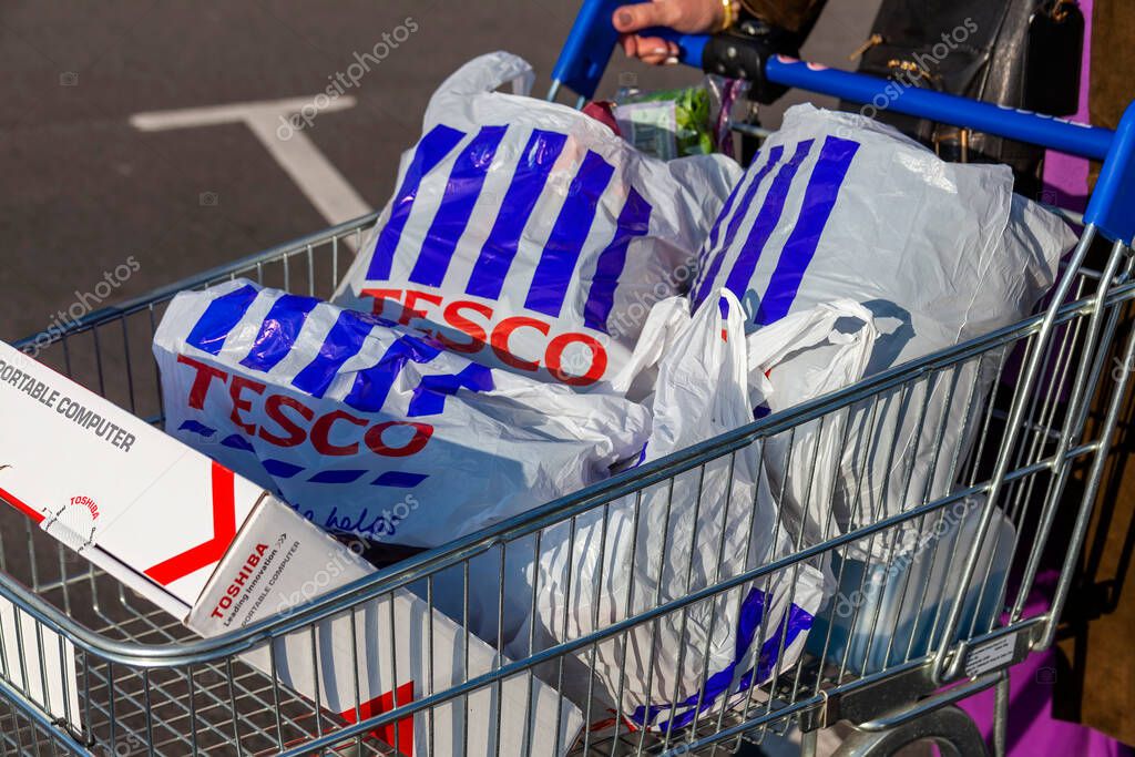 London, UK, November 19, 201 : Customer shopper pushing a shopping trolley cart full of plastic carrier bags at its Tesco Extra supermarket retail business store in Brent Park Wembley stock photo