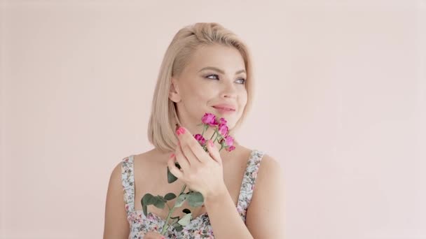 Портрет красивої молодої привабливої блондинки з блакитними очима на яскравому фоні тримає букет з троянд — стокове відео