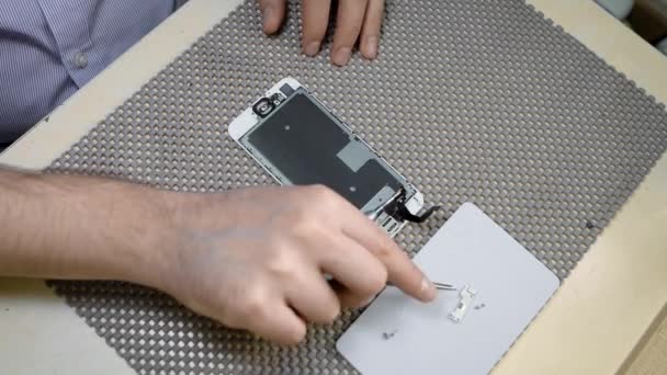 Een telefoon reparateur biedt garantie service voor een kapotte smartphone, vervanging van onderdelen — Stockvideo