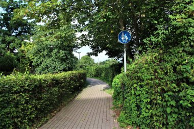 Hegdes tarafından çerçevelenmiş taş geçit. Bir trafik levhası ile sağda ve solda.