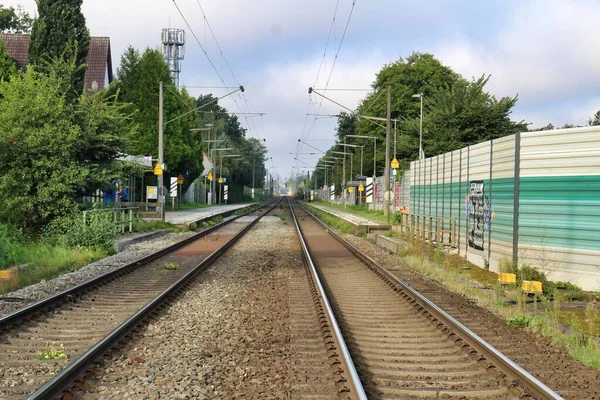 Järnvägsspår med en liten järnvägsstation en skyddsmur och träd — Stockfoto