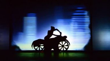 BERDYANSK, UKRAINE - 30 EKİM: motosikletli kız. Mum ve kız. 30 Ekim 2016 'da Ukrayna' nın Berdyansk kentinde arka planda beyaz perdenin önündeki gölgeler tiyatrosunun performansı