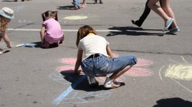 Küçük çocuklar asfalta renkli tebeşir çiziyorlar. Çocuk Günü.