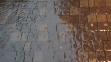 Şehirde yağmur yağıyor. Kaldırıma yağmur damlaları düşüyor..