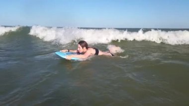 Dalgalarda sörf tahtasında sörf yapan sörfçü kız.