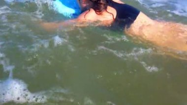 Dalgalarda sörf tahtasında sörf yapan sörfçü kız.