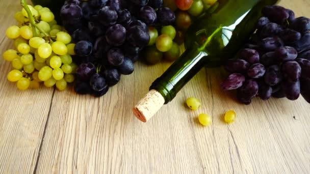 ワインボトルやブドウを背景に 木の板にぶどうの実を落とす スローモーション — ストック動画
