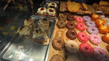 Süpermarkette renkli jöleli çöreklerle, keklerle, tarçınlarla ve diğer fırınlanmış yiyeceklerle kaplı bir vitrin..