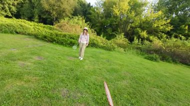 Genç bir kız, yeşil çimlerin üzerinde, yaz çimlerinde badminton oynuyor. Ağır çekim. Bakış açısı.