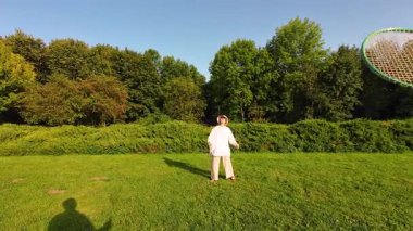 Genç bir kız, yeşil çimlerin üzerinde, yaz çimlerinde badminton oynuyor. Bakış açısı.