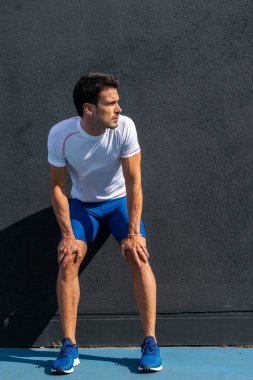 Mavi pantolonlu, beyaz gömlekli, siyah duvarda dinlenen genç bir adam. Motivasyon konsepti, kariyer