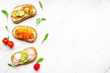 Kahvaltı, atıştırmalık, aperatif, avokado, turp, domates, pastırma, salatalık, krem peynir, tam tahıllı sandviç. Hafif bir arkaplanda, boşluğu kopyala