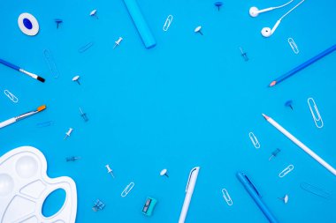 Okul konseptine geri dönelim. Üst düzey okul gereçleri ve kırtasiye malzemeleri mavi arka plandaki öğrenci masasında. Düz yat ve boşluğu kopyala