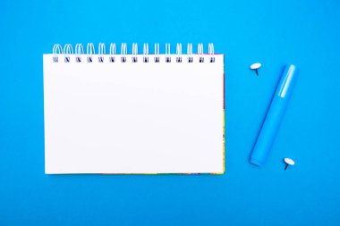 Minimalist okul ya da ofis konsepti. % 1 konumundaki not defteri ve kırtasiyenin üst görünümü mavi arkaplan üzerinde kopya alanı ile