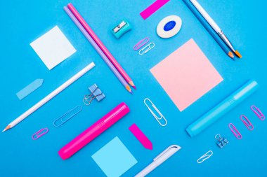 Okul konseptine geri dönelim. Üst düzey okul gereçleri ve kırtasiye malzemeleri mavi arka plandaki öğrenci masasında. Düz yat ve boşluğu kopyala