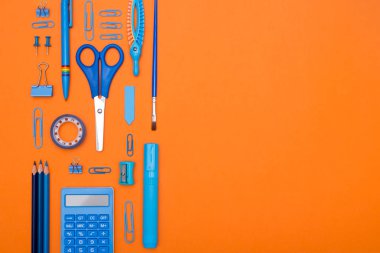 Okul konseptine geri dönelim. Üst düzey okul malzemeleri, turuncu arka plandaki öğrenci masasında. Düz yat ve boşluğu kopyala