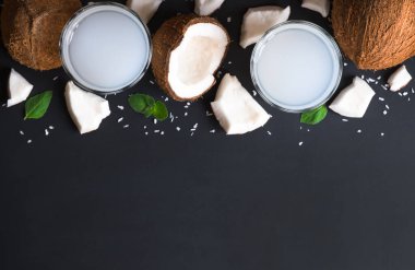 İki bardakta hindistan cevizi suyu ve koyu arkaplanda malzemeler. Sağlıklı vejetaryen içeceği. Boşluğu kopyala.