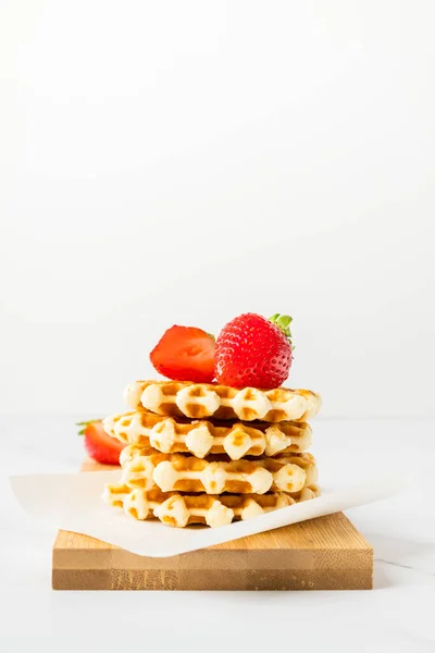Fresh traditional belgian waffles with soft cheese and berries on a light table with copy space