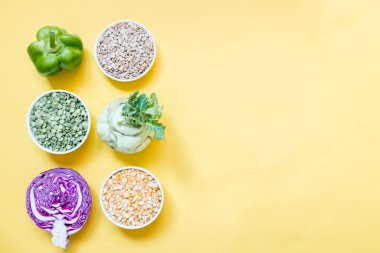 Vejetaryen gıda konsepti. Yeşil, kırmızı sebzeler ve sarı arka planda protein serisi. Boşluğu ve düzlüğü kopyala