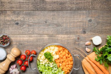 Bir tencerenin üst görüntüsü ve fotokopi alanından sebze çorbası yapmak için çeşitli taze sebze malzemeleri.