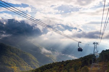 Gazprom, Krasnaya Polyana, Sochi, Rusya - 09 Eylül 2020: Günbatımında bir dağ manzarasının arka planına karşı teleferik.