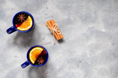Üst manzara iki kupa sıcak şarap baharat ve portakal dilimleri ile gri arka planda kopya alanı ile.