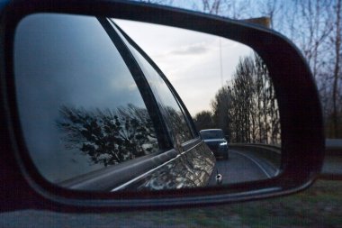 Arabadaki aynaya bak, bir arabanın ön camından geçen gece yoluna.