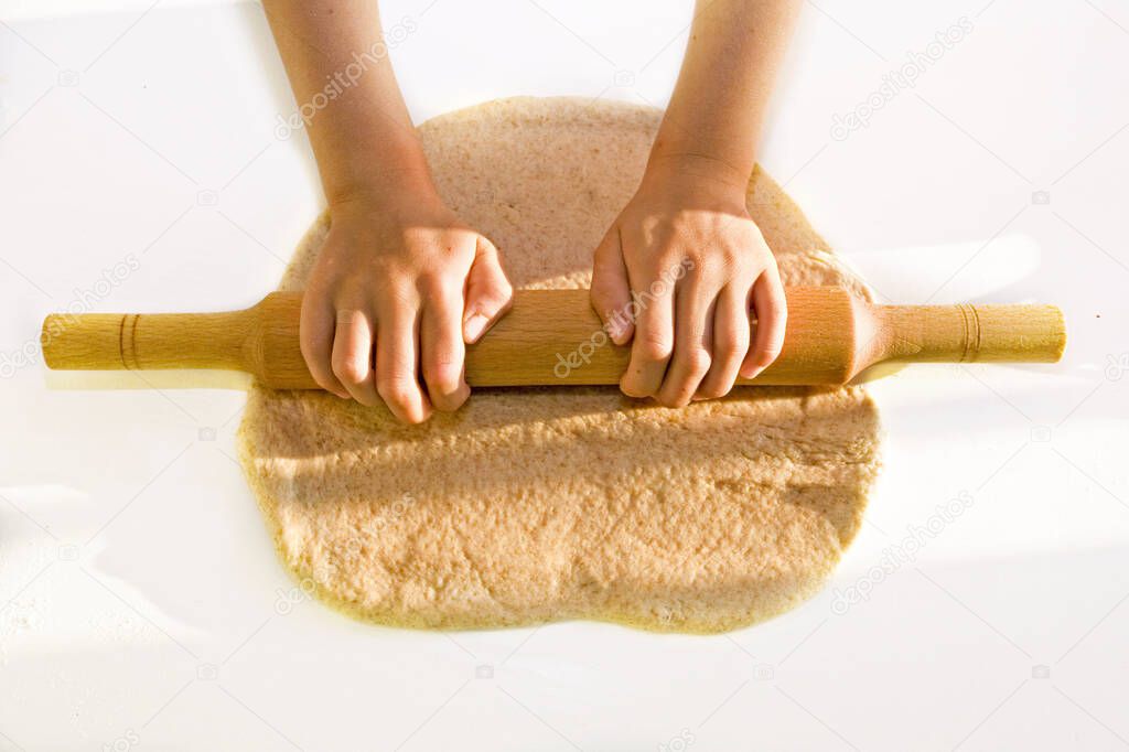 The girl rolls the dough in the sun