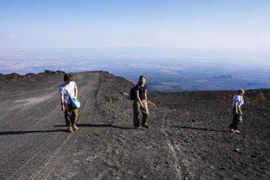 Mutlu gençler sabahın erken saatlerinde Etna yanardağının kraterlerine yürür. Aktif okul tatili