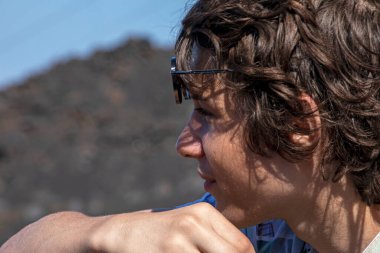 Dağın zirvesindeki mutlu genç çocuk uzaklığa bakıyor. Zirveyi fethetmek