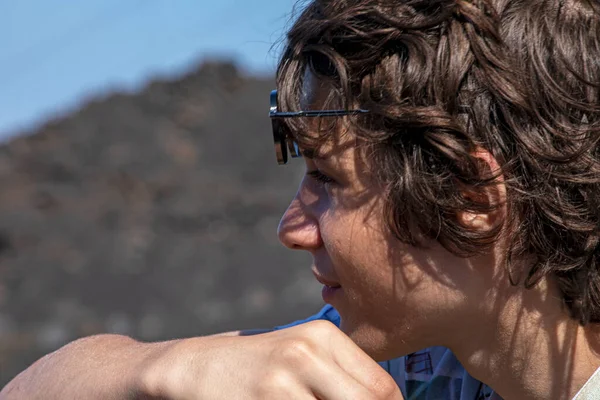 Dağın zirvesindeki mutlu genç çocuk uzaklığa bakıyor. Zirveyi fethetmek