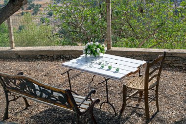 Gün boyunca bahçedeki bir masada şamdanlı beyaz çiçekler.