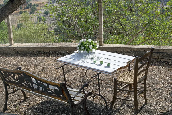 Gün boyunca bahçedeki bir masada şamdanlı beyaz çiçekler.