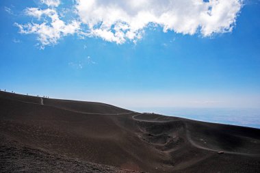 Tourists on the ridge of one of the craters of Mount Etna. Educational excursion
